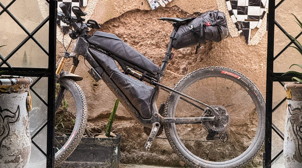 Gravelbike mit Taschen an rustikaler Wand
