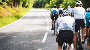 Gruppe von Rennradfahrern auf Landstraße im Grünen